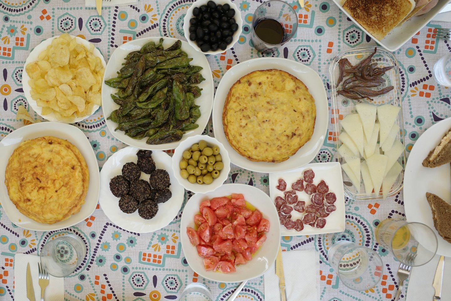 Varios platos de tapas españolas dispuestos sobre una mesa de comedor estampada.