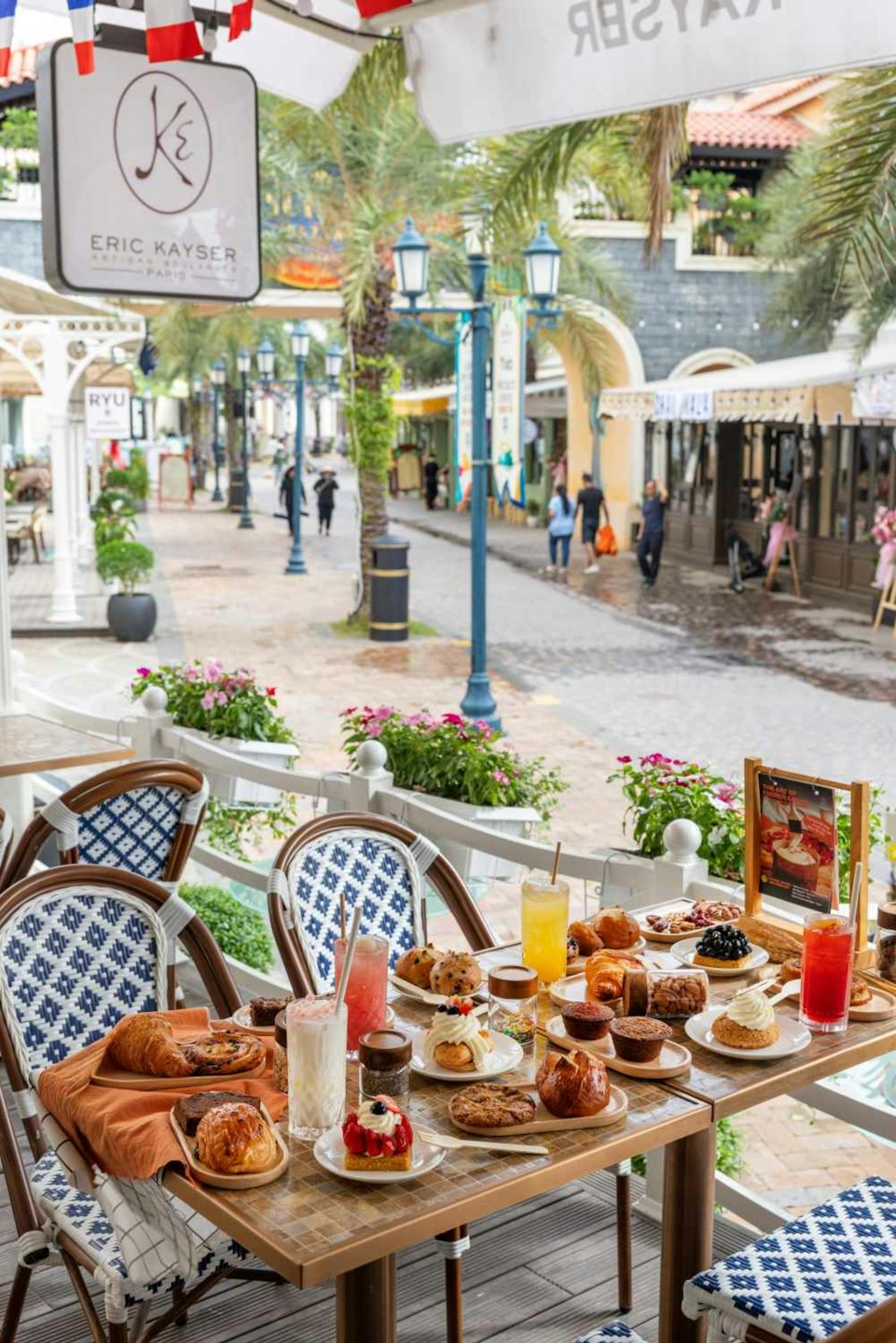 Pasteles y bebidas en una mesa de cafetería con vistas a la calle.