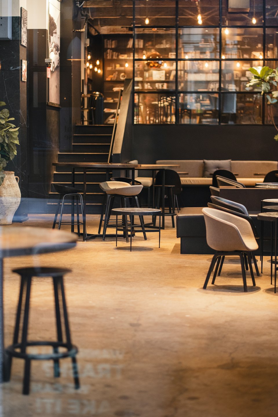 Cafetería moderna y vacía con asientos elegantes y bombillas Edison.